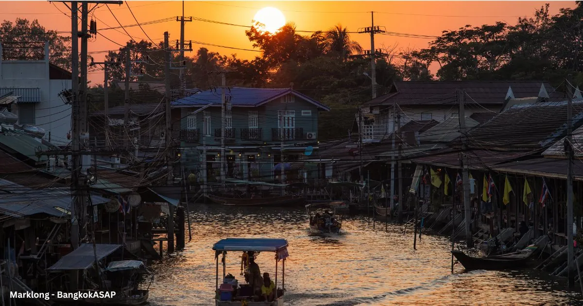 Stilt houses and a small boat on the Amphawa canal in evening light